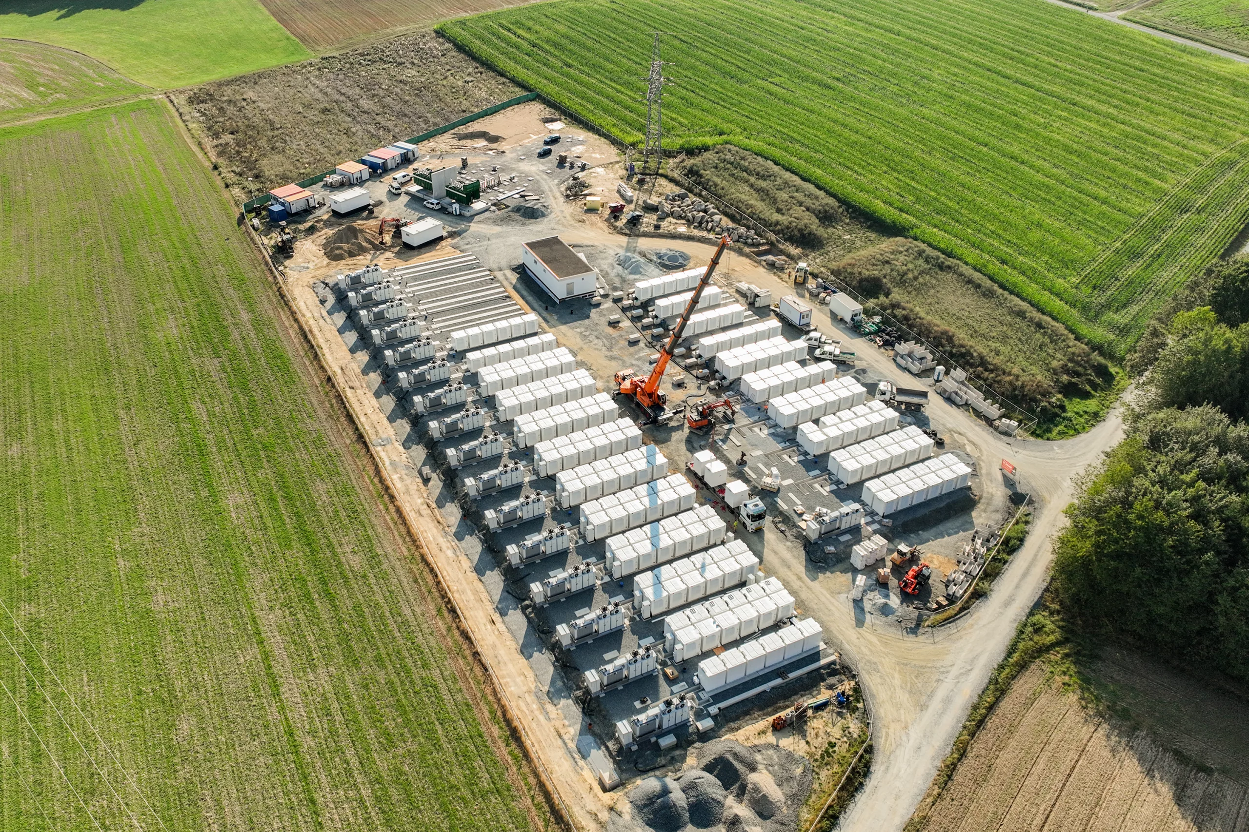 Aerial view of the Arzberg battery storage facility with white containers arranged in rows and a construction crane on site.